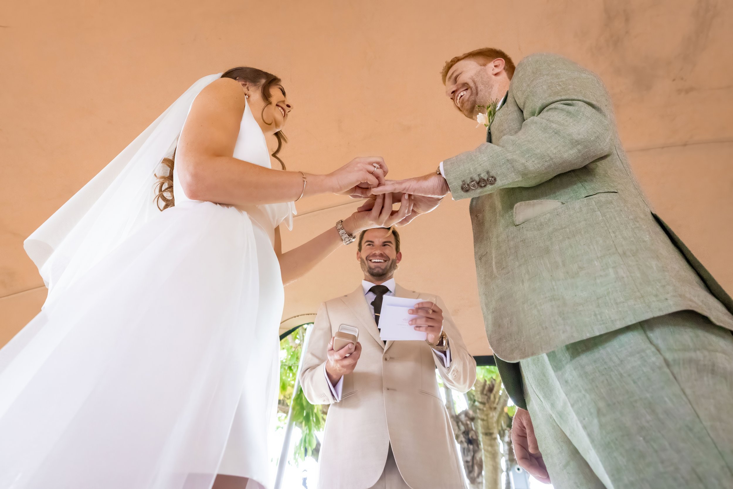 bride puts ring on groom's finger during wedding ceremony