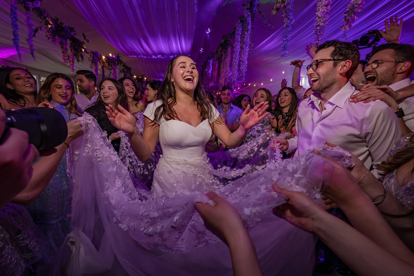 Bride dancing energetically in Nunsmere Hall marquee, purple lighting
