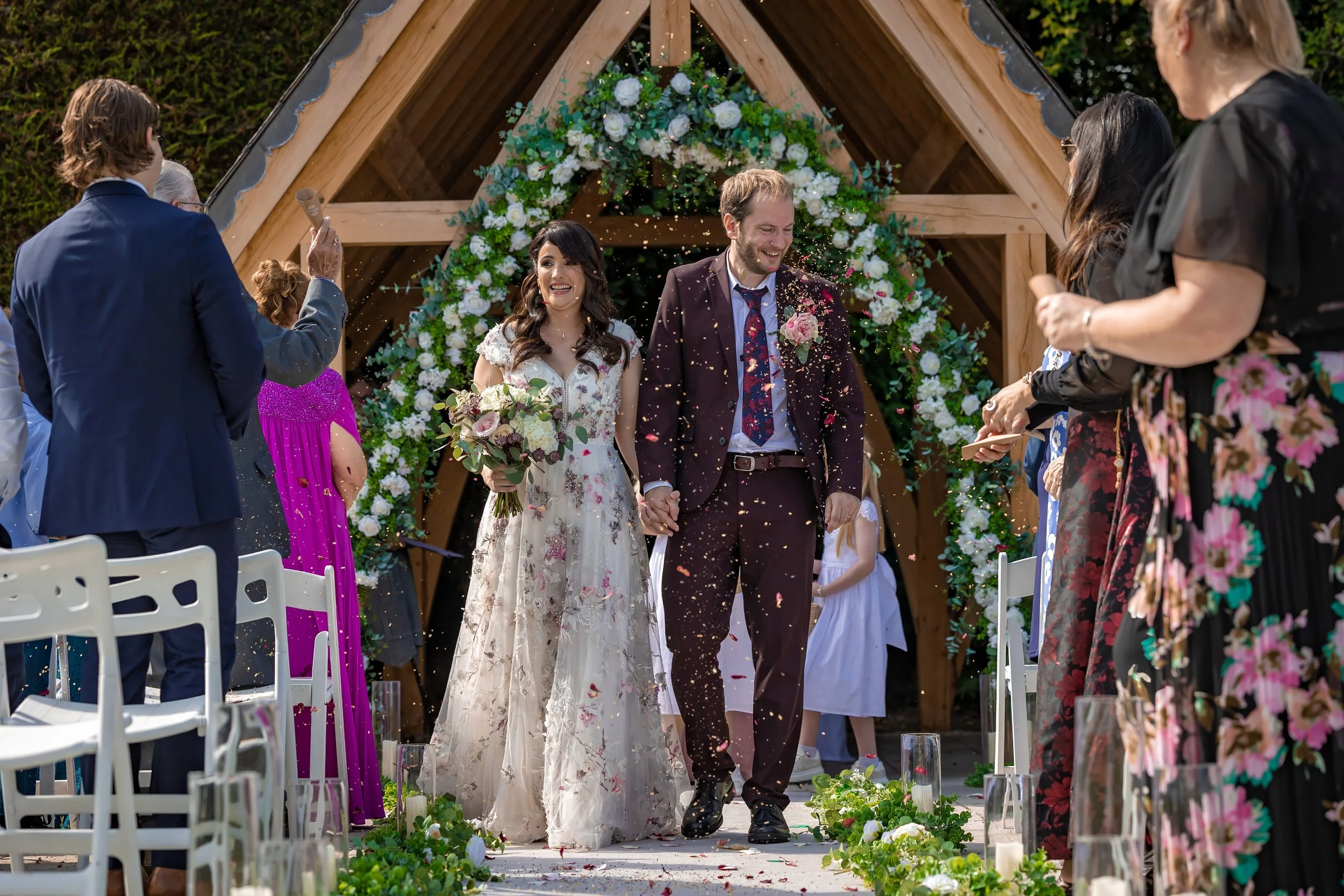 Bride and groom end wedding ceremony with confetti run surrounded by guests