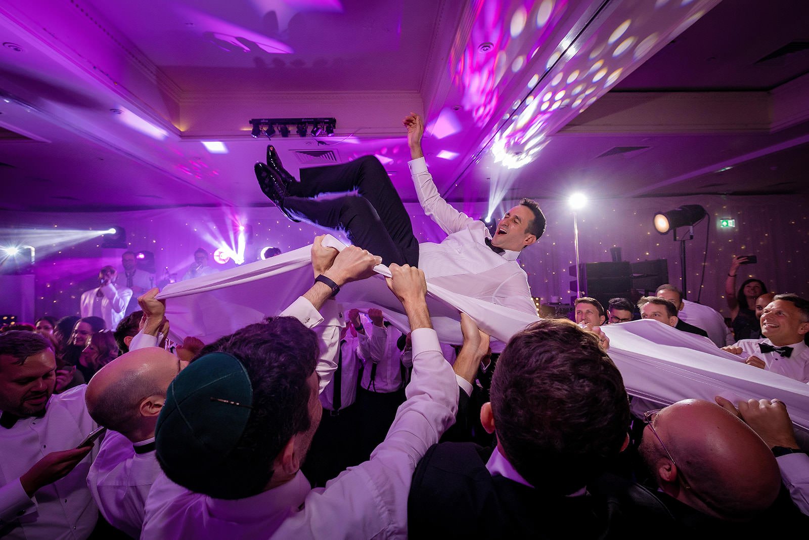 groom thrown in air during reception dancing at mere golf resort in cheshire