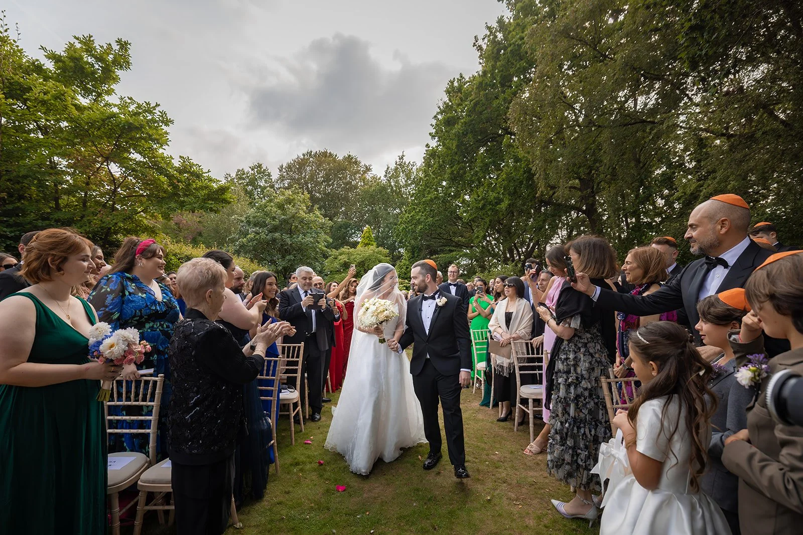 bride and groom walk on aisle during outdoor wedding ceremony at nunsmere hall in cheshire