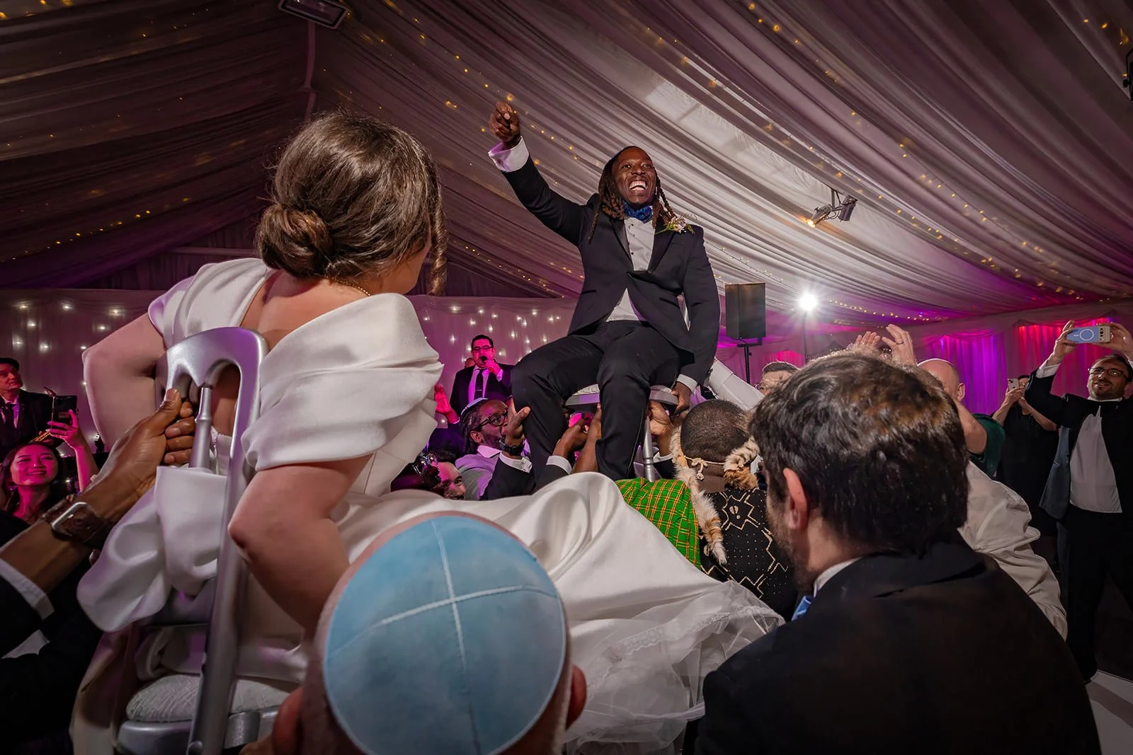 bride and groomlifted on chairs during wedding reception dance floor at heaton house farm