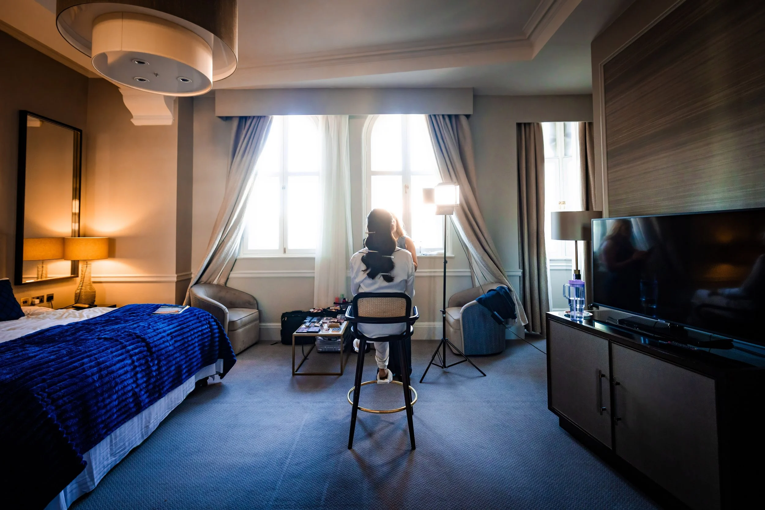 bride getting ready in front of window during bridal prep at midland hotel manchester