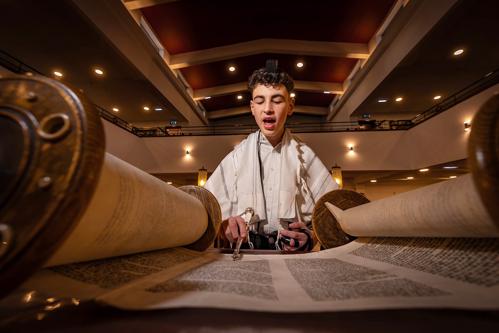 barmitzvah boy on bimah reciting from torah in synagogue in Manchester