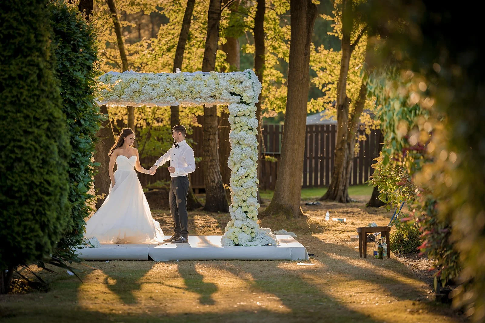 Bride and groom at outdoor ceremony arch in autumn light, Nunsmere Hall Cheshire
