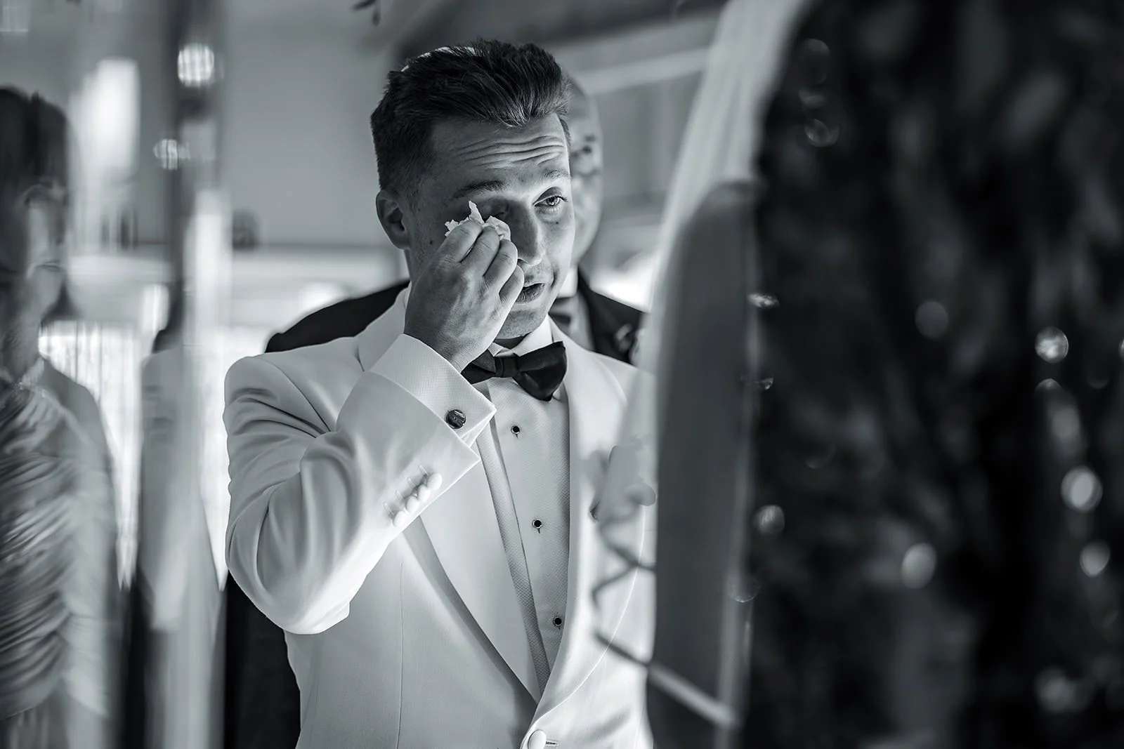 Merrydale Manor wedding groom in white tuxedo wiping eye during emotional ceremony