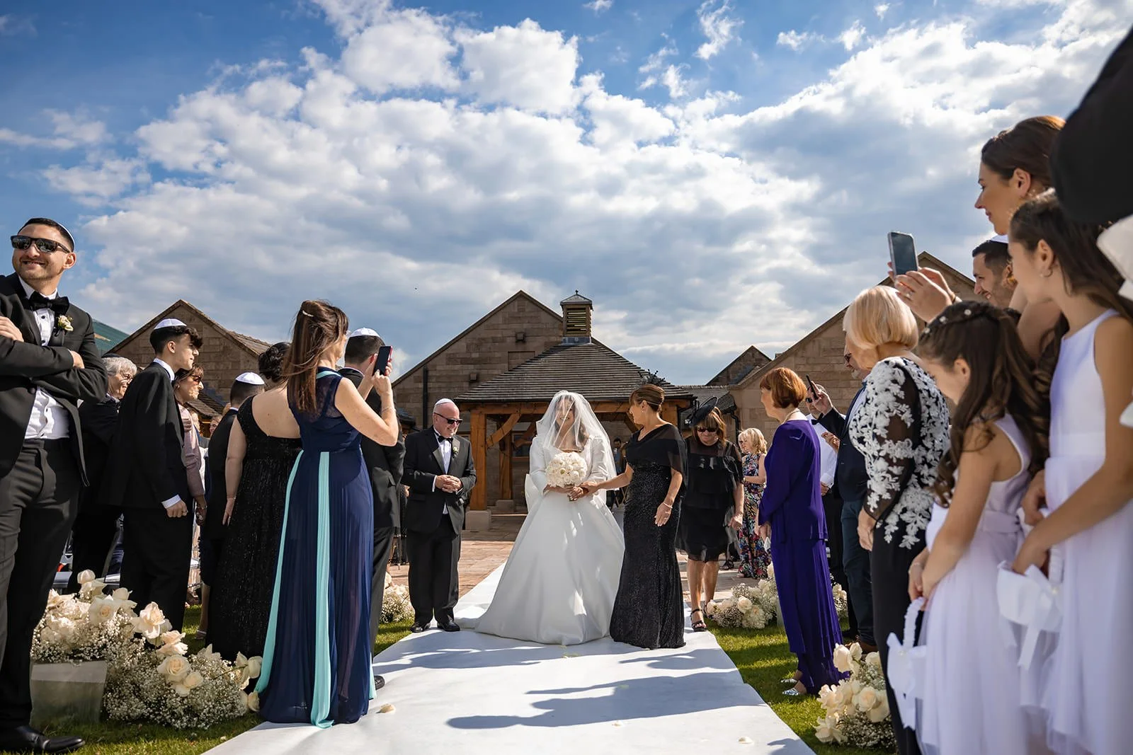 bride and father walk down aisle during outdoor wedding ceremony at heaton house farm in macclesfield