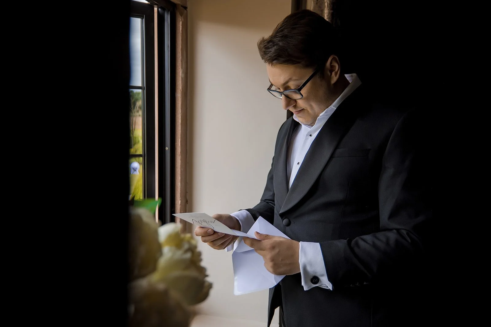 Merrydale Manor wedding groom reading card by window – documentary wedding photographer Manchester