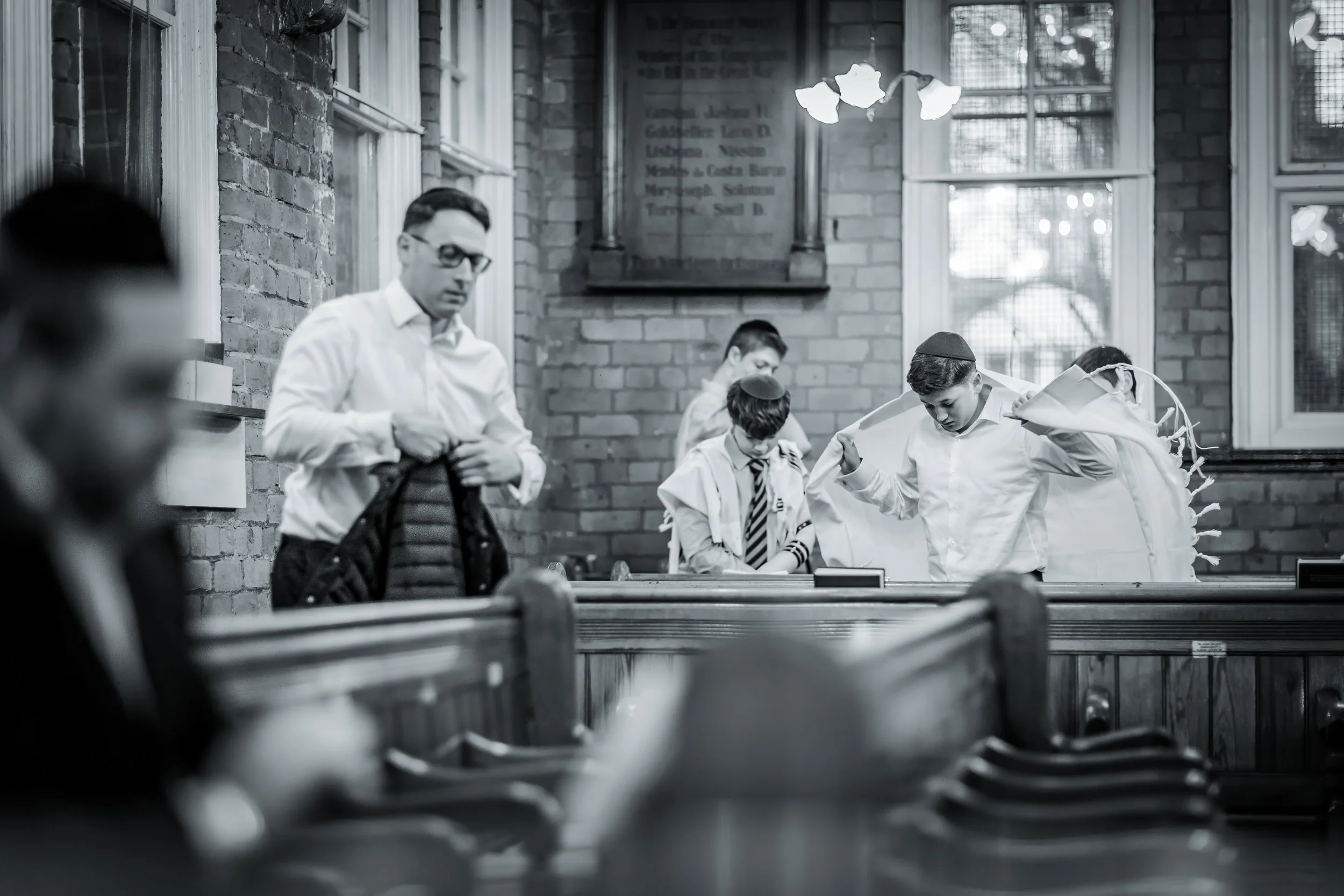 barmitzvah boy puts on tallit in synagogue before ceremony