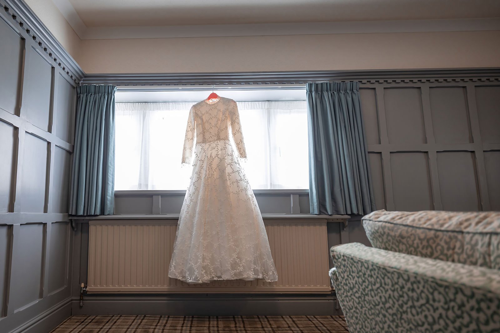 wedding dress hanging in window during bridal prep at last drop village in bolton