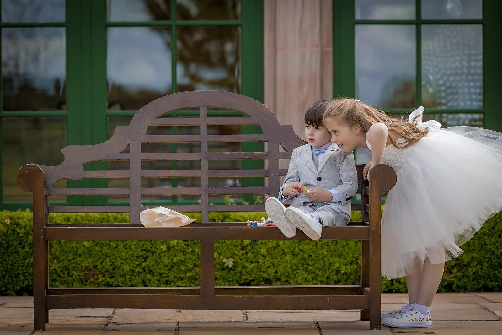 Merrydale Manor wedding flower girl whispering on wooden bench – wedding photography North West