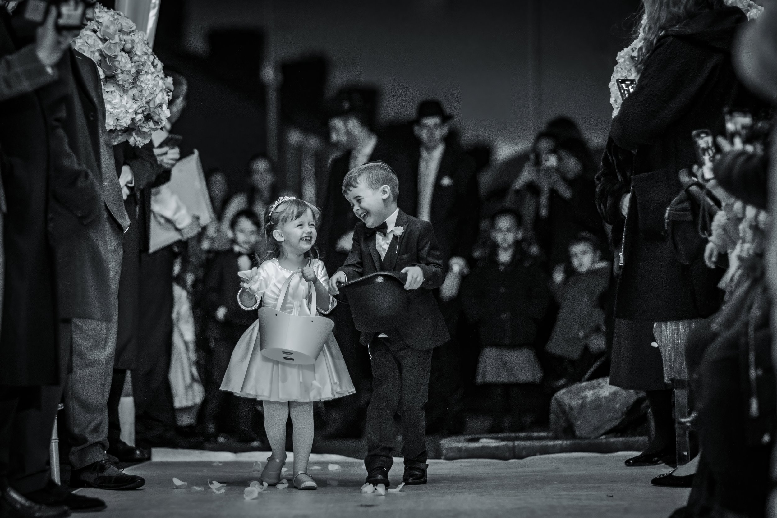 documentary style wedding photograph of pageboy and flower girl walking down aisle in Manchester