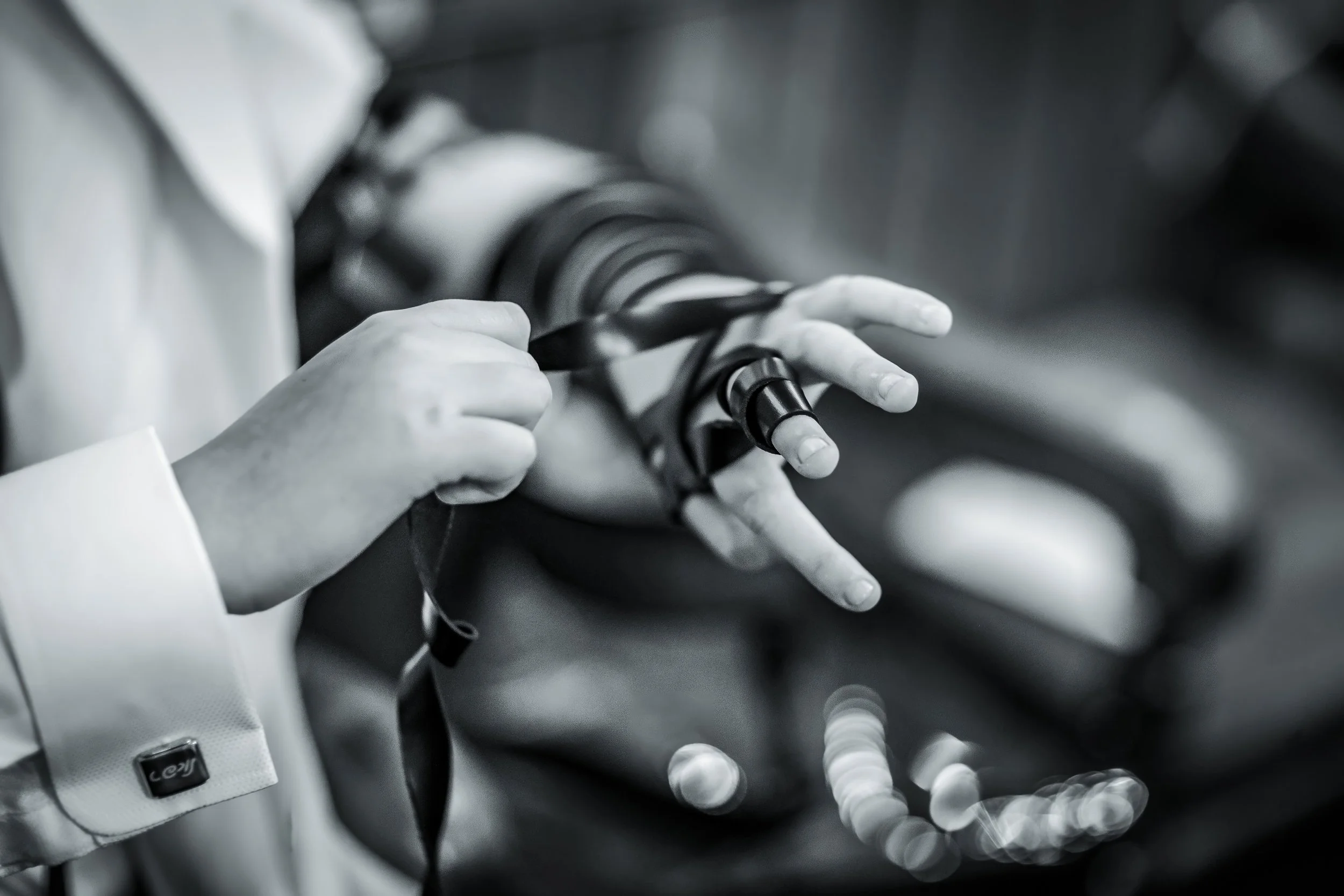 black and white detail of barmitzvah boy putting tefillin on hand