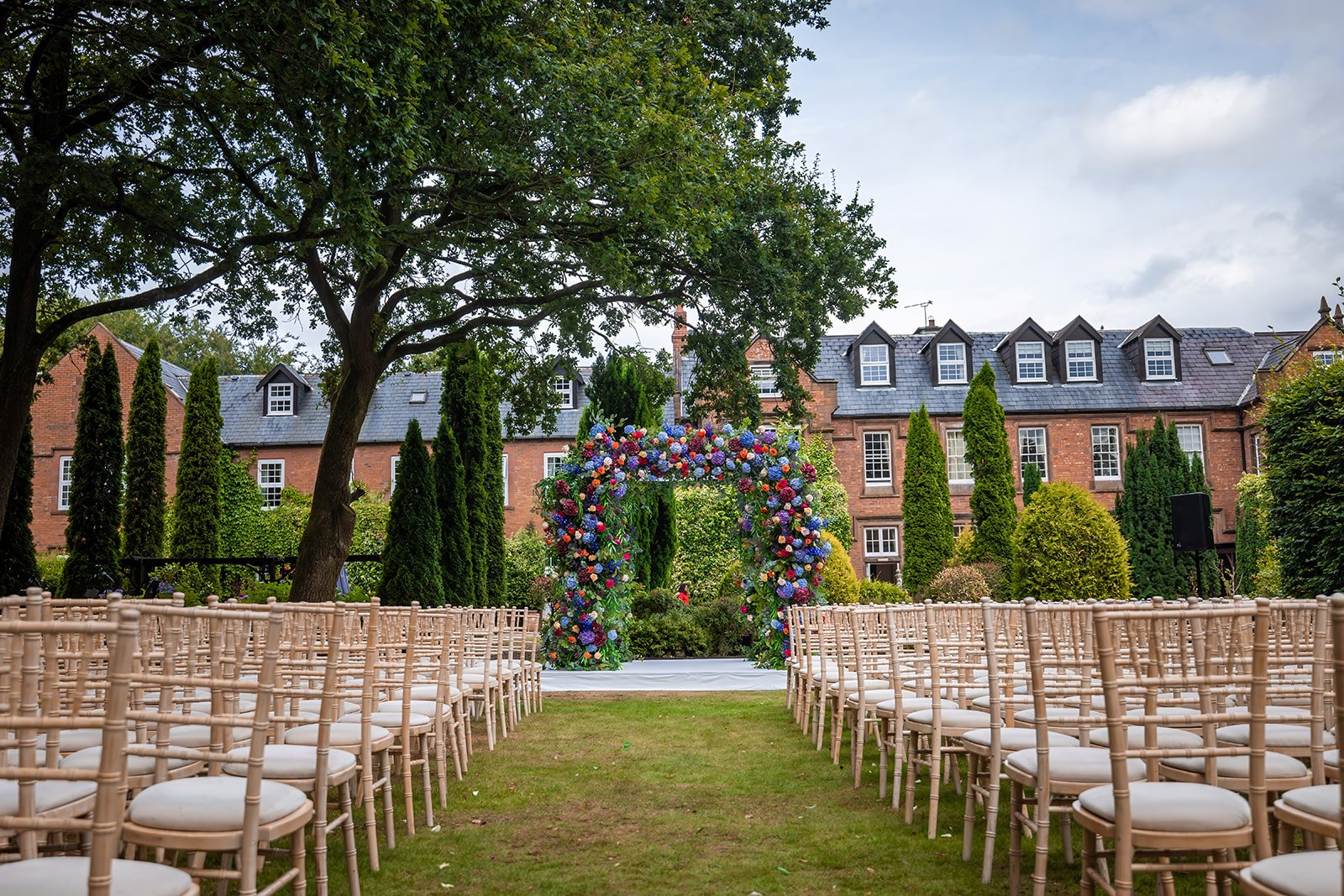 Empty outdoor ceremony setup with wooden chairs and white aisle, Nunsmere Hall
