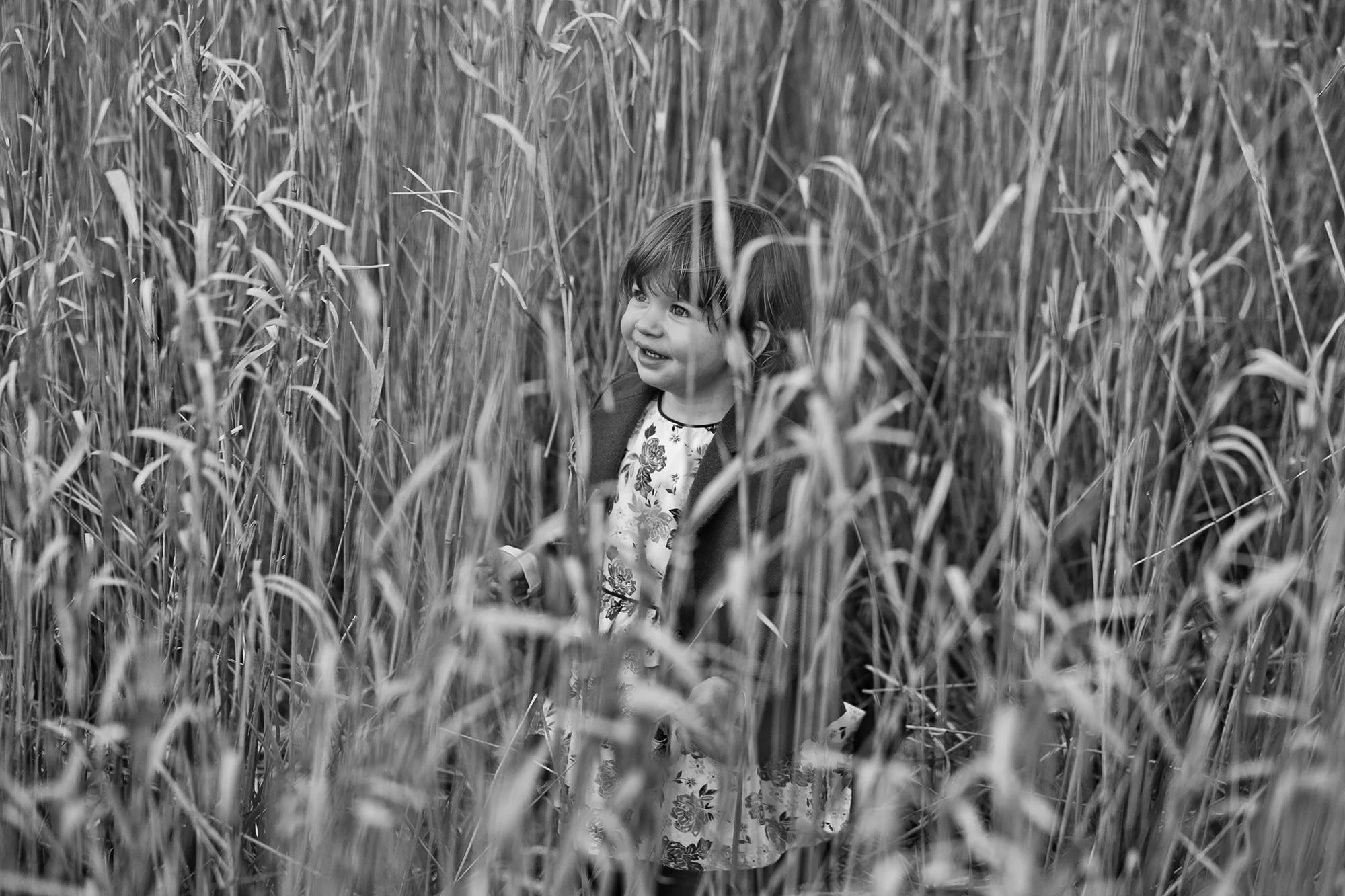 black and white portrait of young girl in long grass field