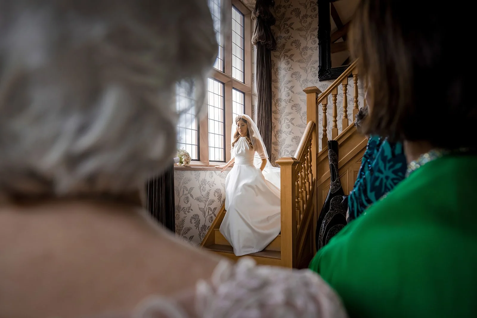 A bride at Merrydale Manor comes down staircase to see bridesmaids