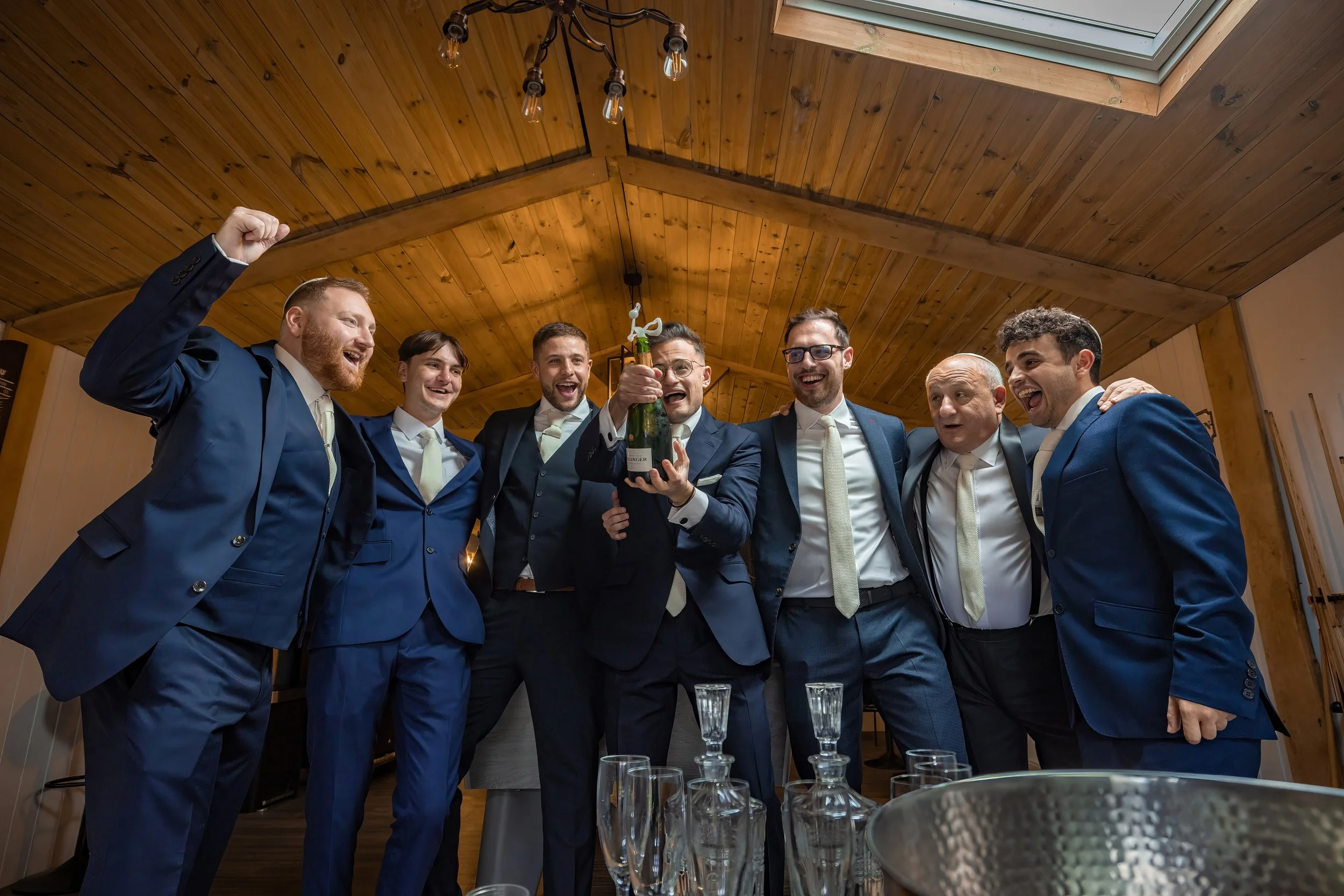 groom and groomsmen open champagne in cave during prep at merrydale manor in cheshire