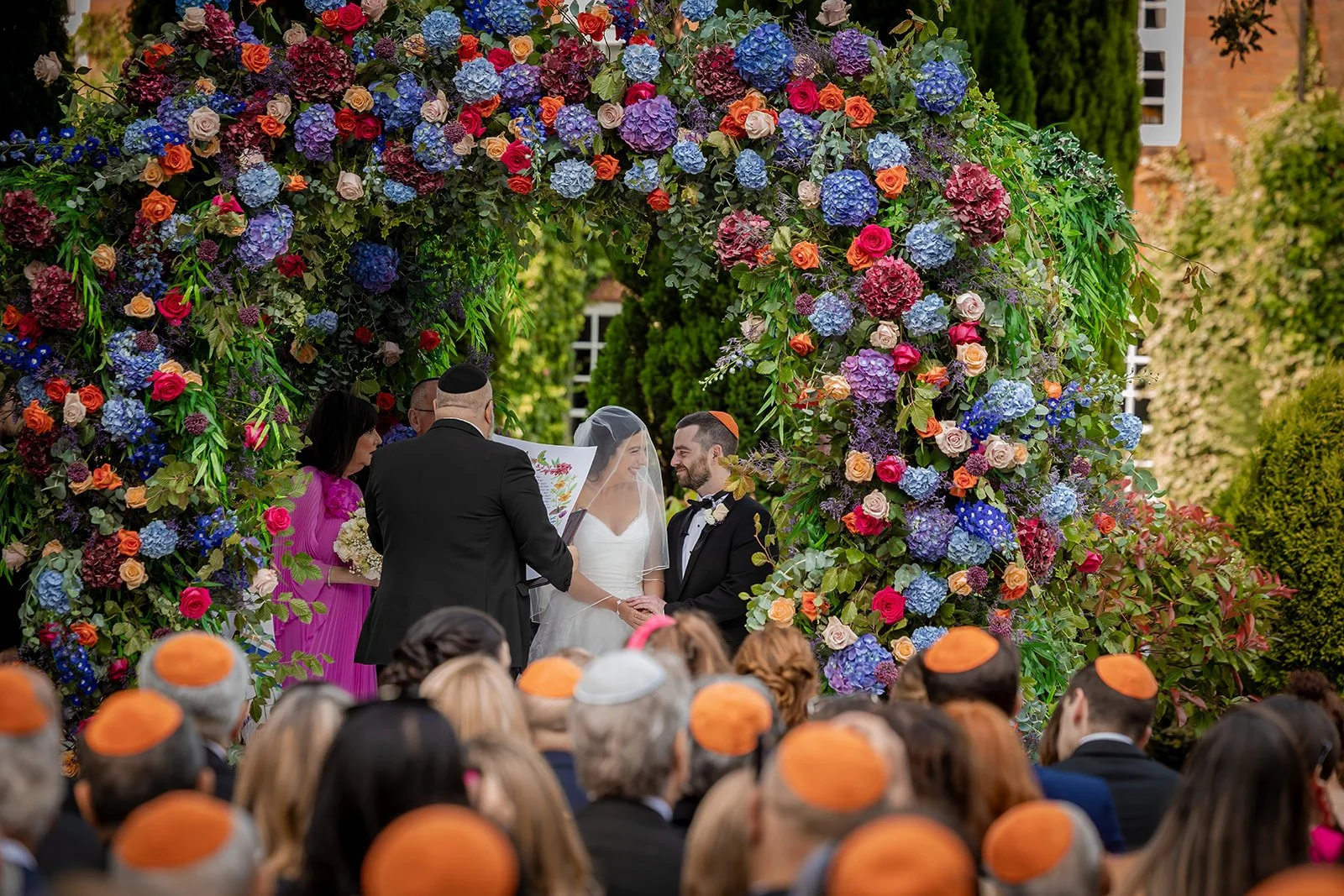 bride and groom exchange vows during floral outdoor wedding ceremony at nunsmere hall in cheshire