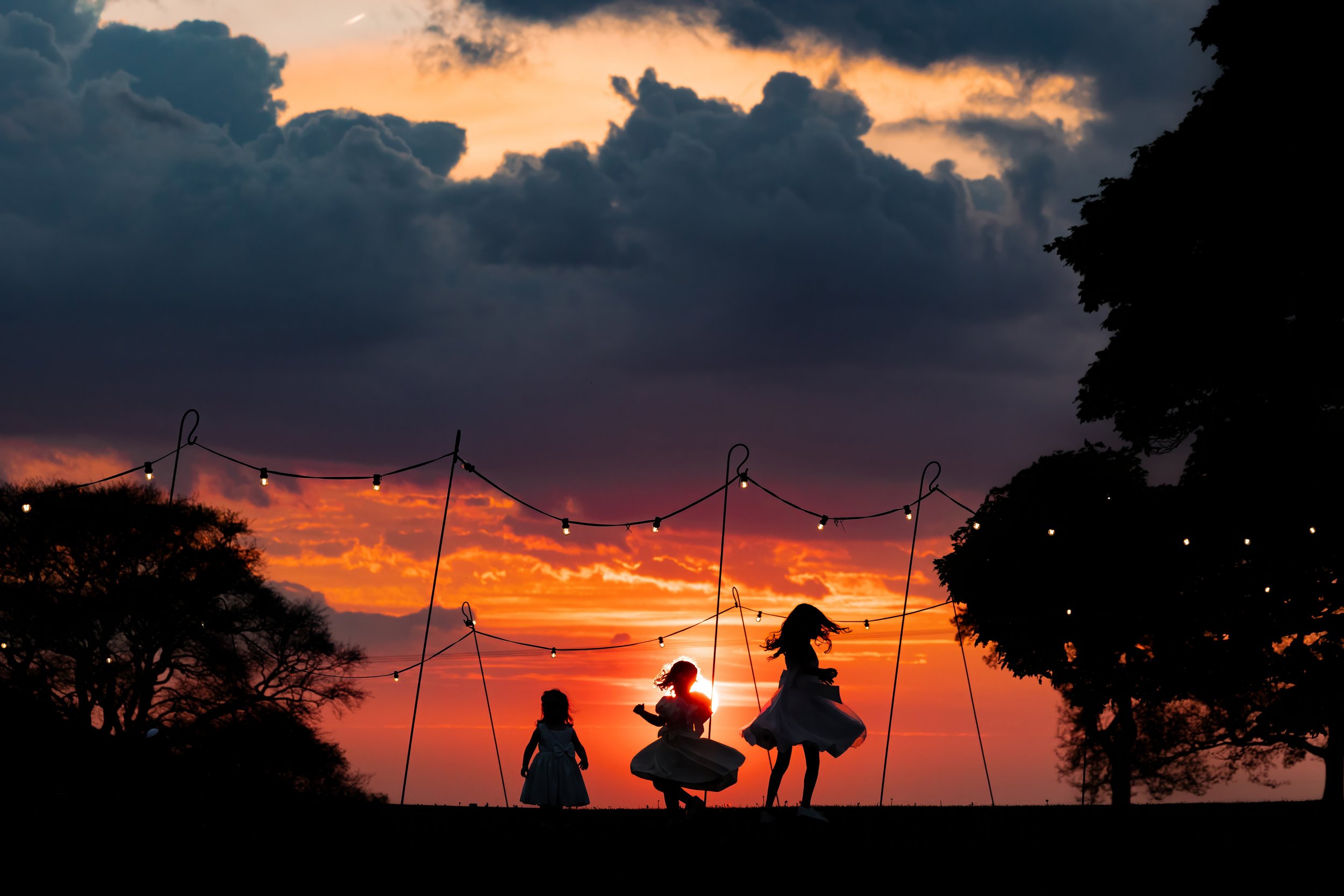 bridesmaids silhouette dancing in red sunset at heaton house farm wedding venue