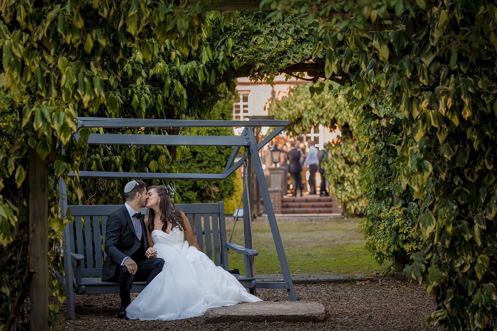 Bride and groom by garden swing in Nunsmere Hall grounds, natural portrait
