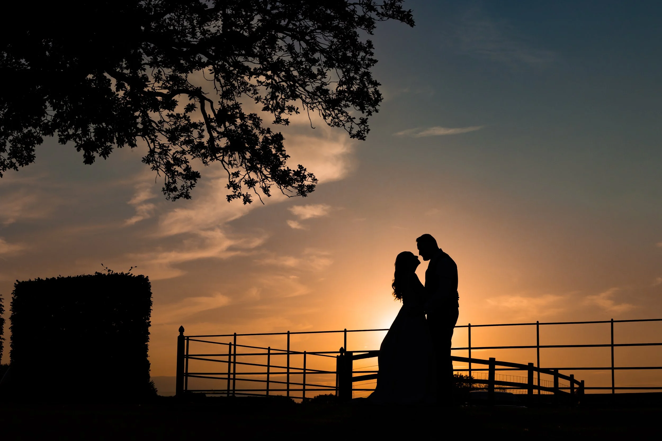 Silhouette of newlyweds at sunset by the gates at Merrydale Manor wedding
