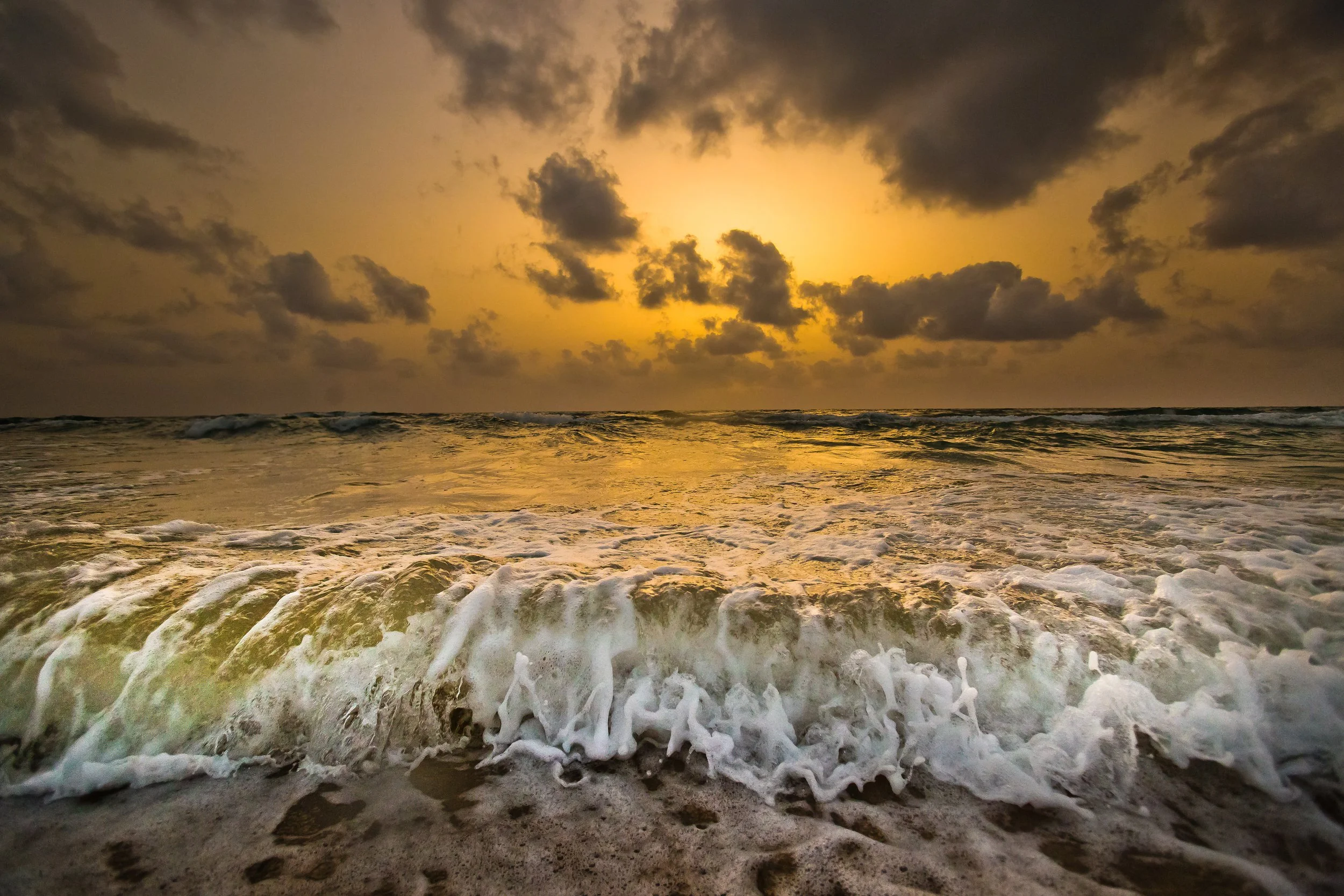 wave breaking on beach with sunset