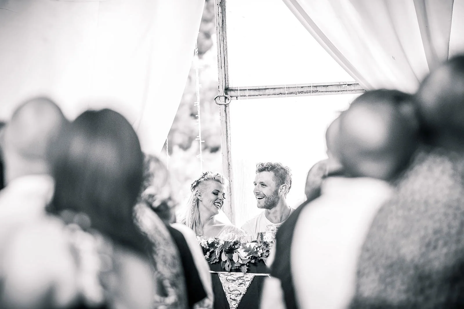 Bride and groom react to wedding speeches framed by guests