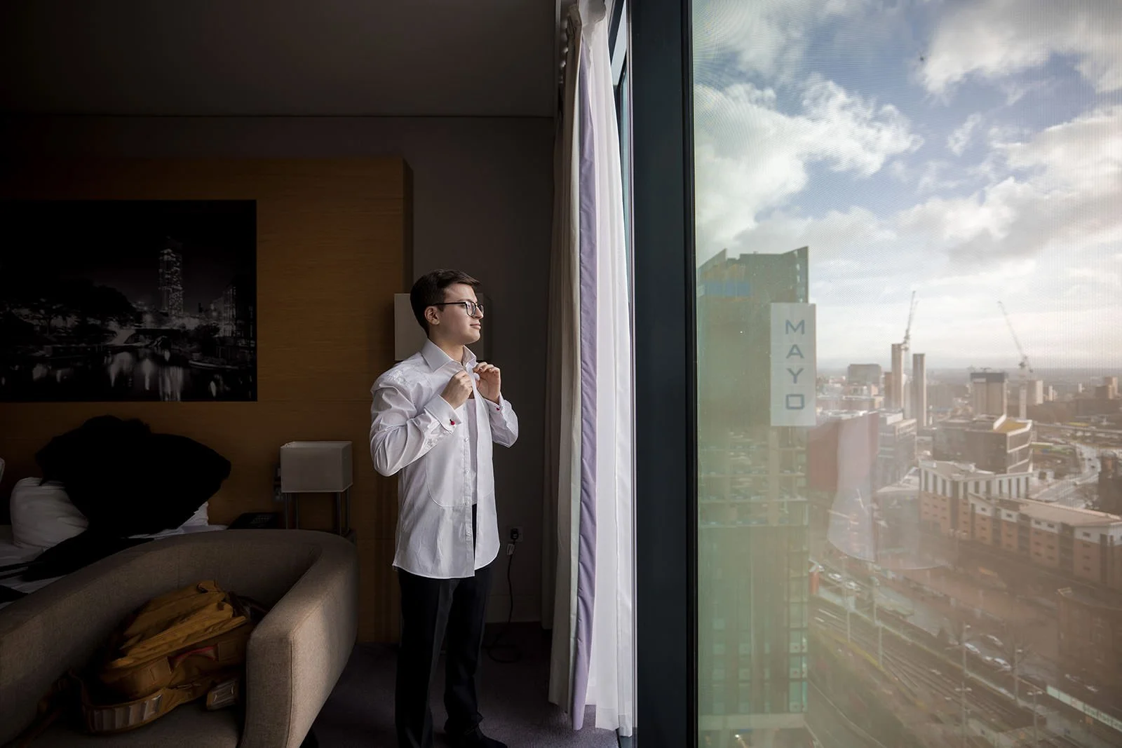 groom getting ready during prep at manchester deansgate hotel wedding venue with city view