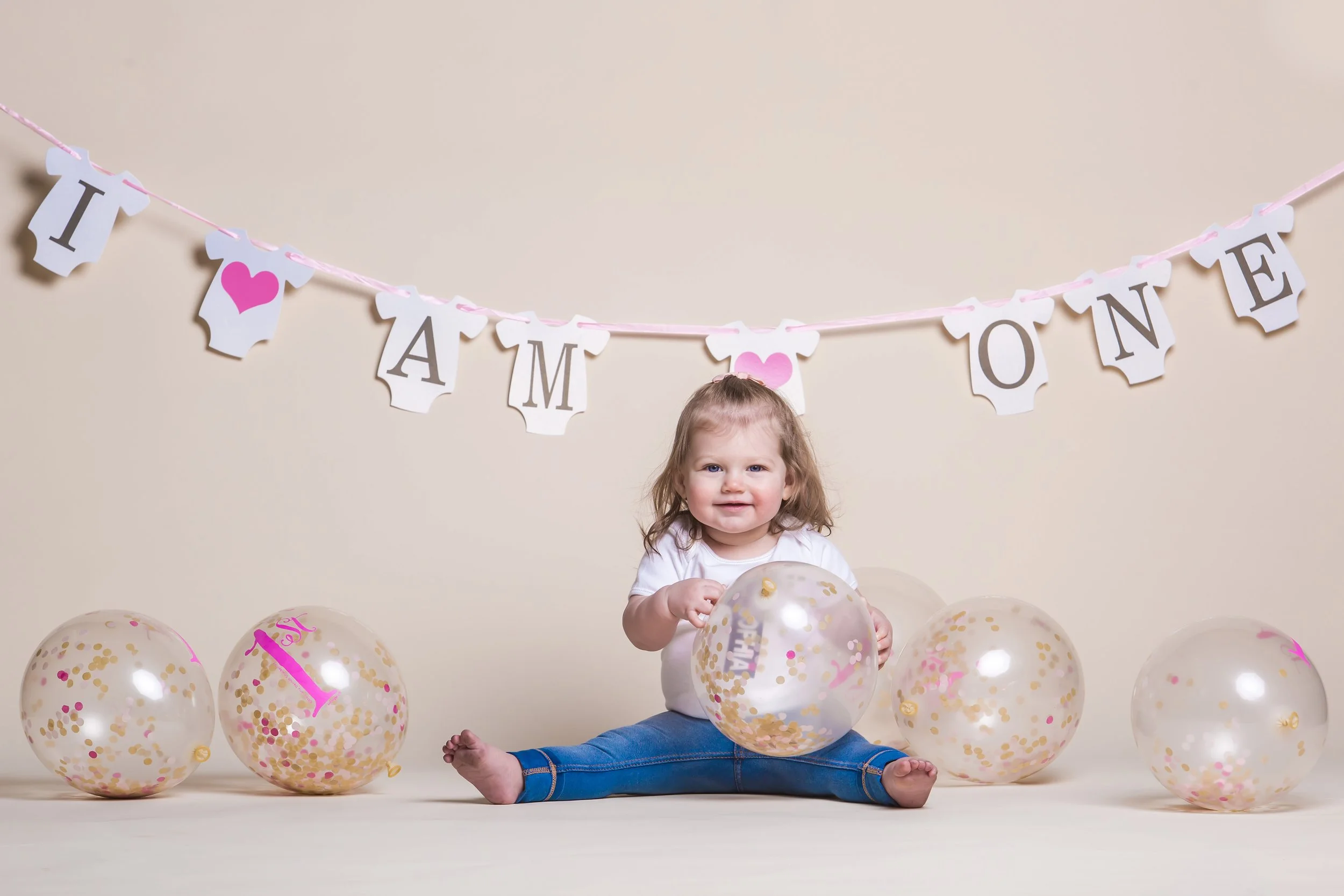 1st birthday baby portrait with balloons in studio