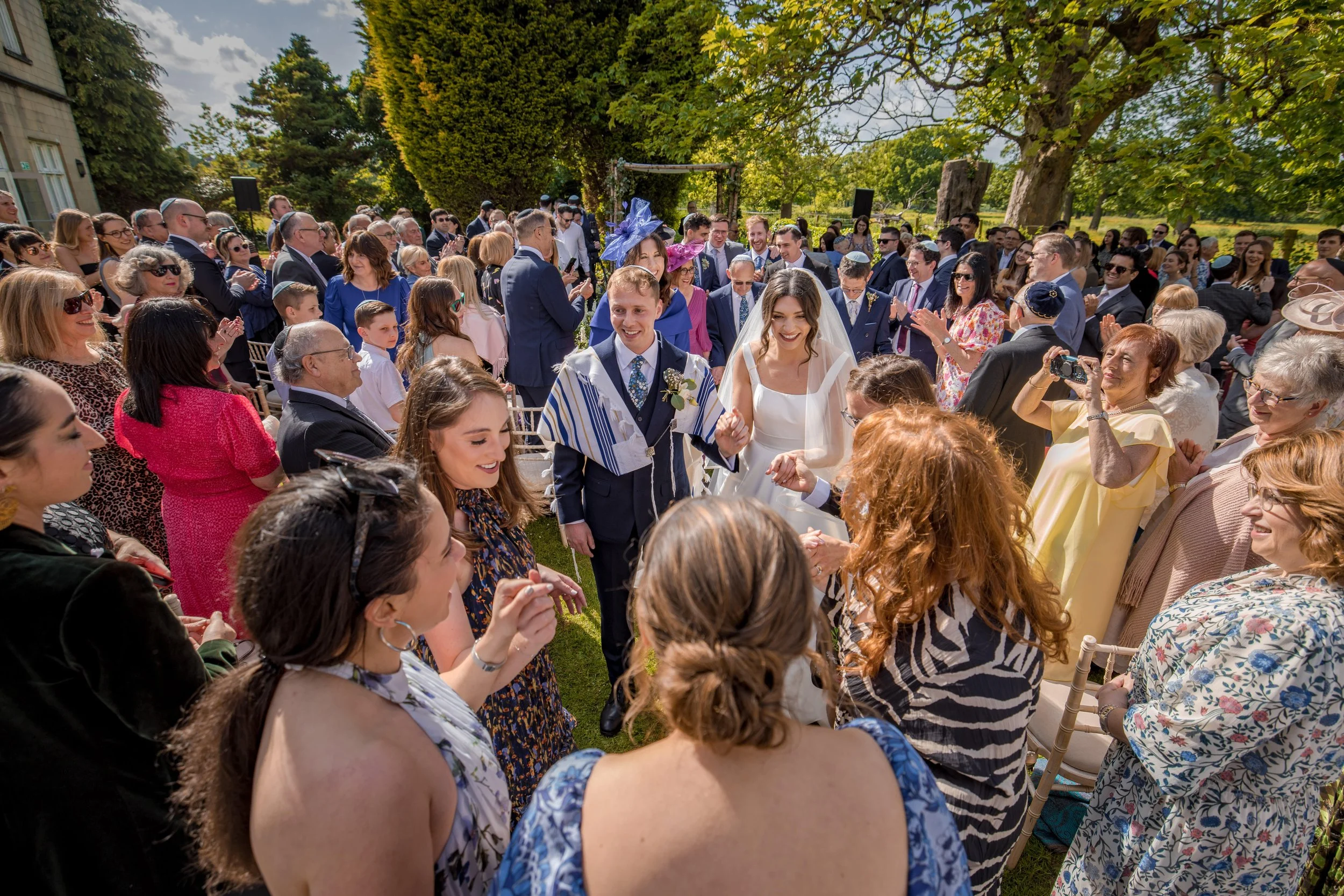 Jewish Manchester wedding photographer captures bride and groom leaving the chuppah after Jewish ceremony