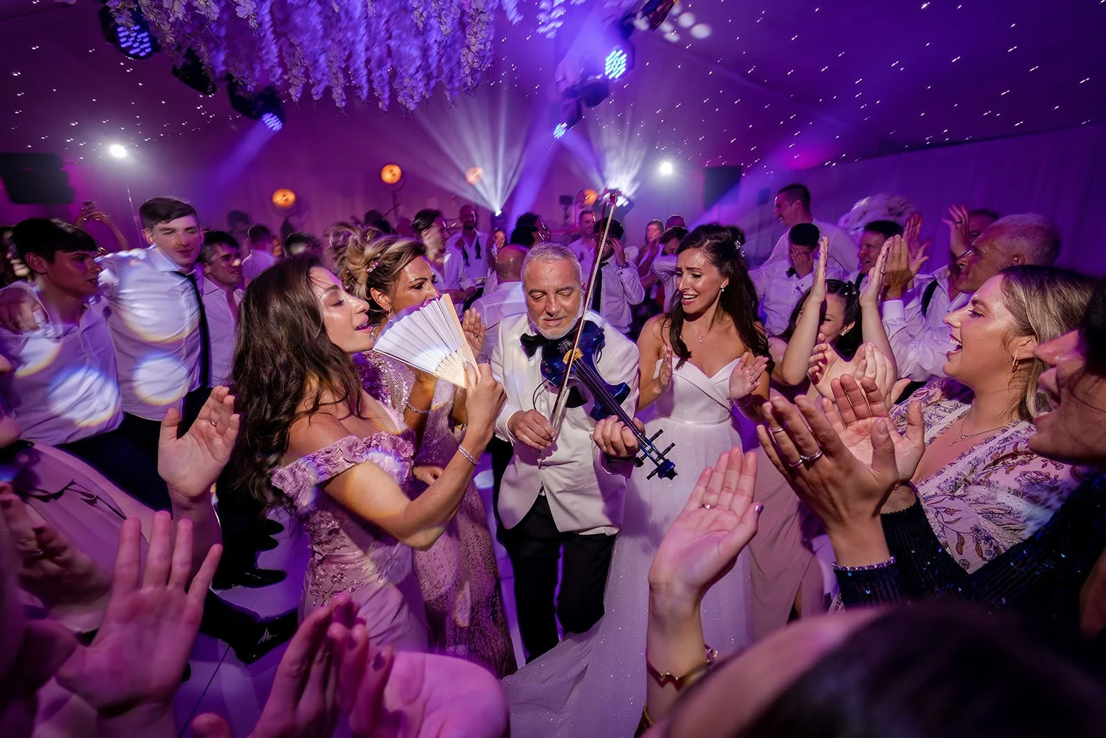 Full dance floor with guests celebrating under pink lighting, Nunsmere Hall marquee
