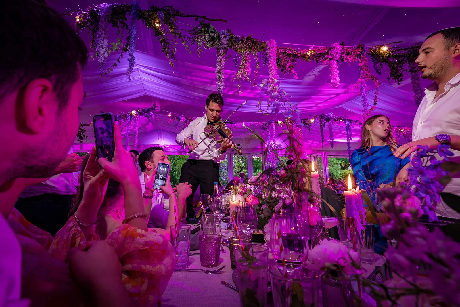 Entertainer performing at table during Nunsmere Hall wedding reception, pink lighting
