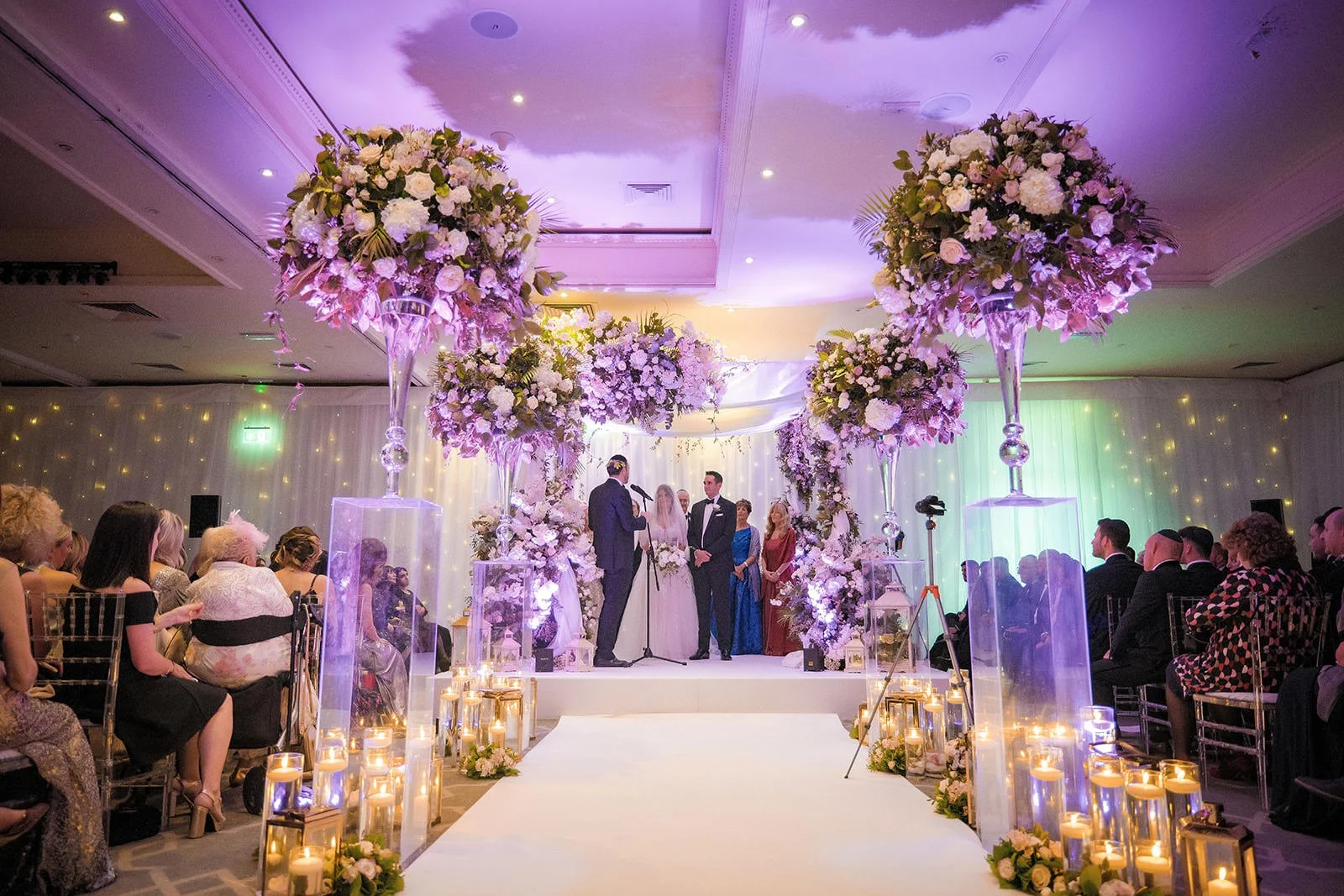 Groom walking down the aisle with candles and tall floral stands, The Mere ceremony
