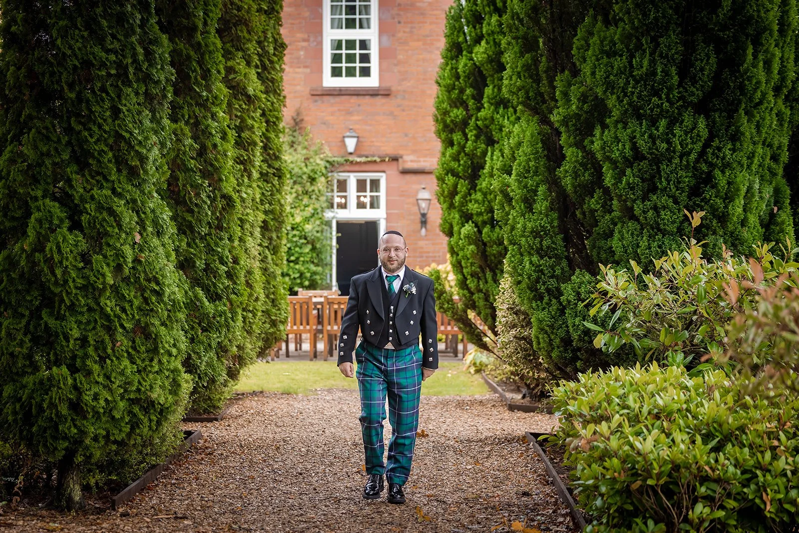 groom walking along gravel path between tall topiary hedges, Nunsmere Hall