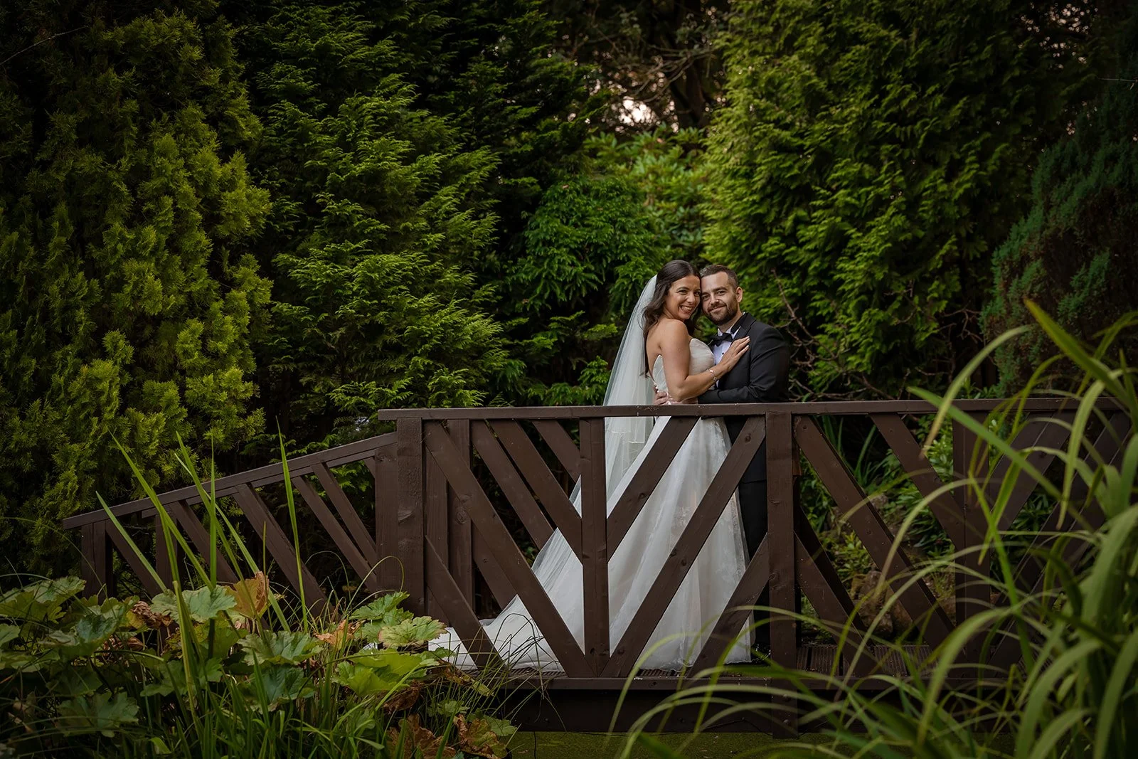 Bride and groom on wooden garden bridge, Nunsmere Hall grounds
