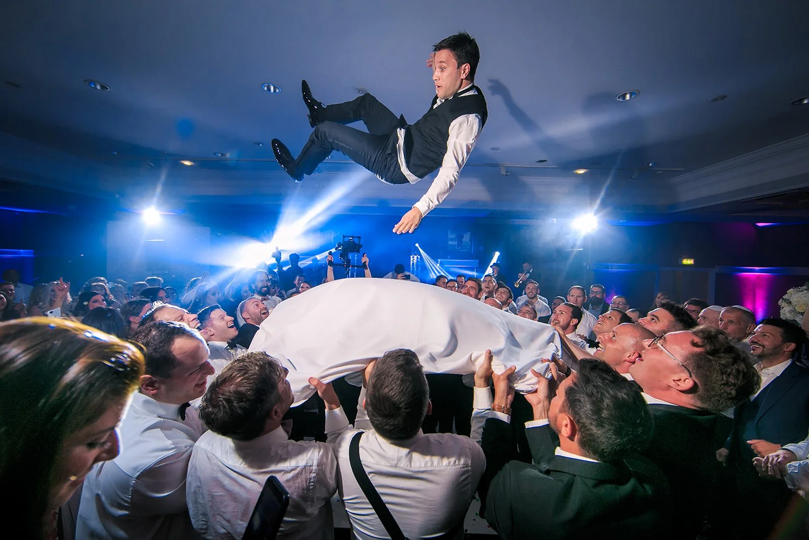 groom thrown high in air on sheet during wedding party at midland hotel