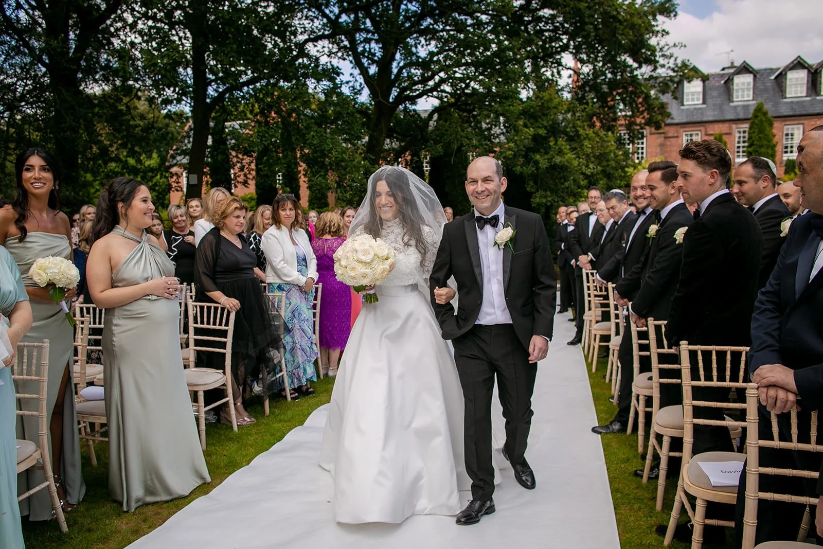 Bride walking down the aisle at outdoor garden ceremony, Nunsmere Hall Cheshire