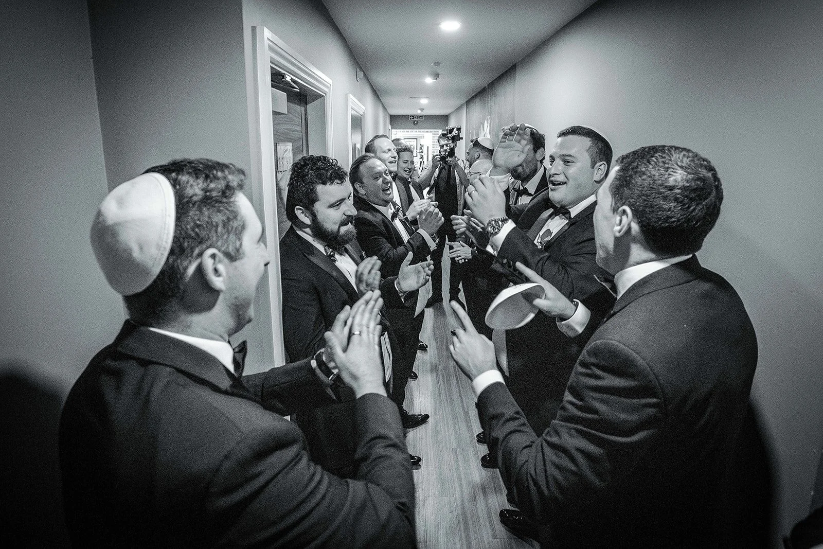 Merrydale Manor wedding groomsmen in hallway celebrating black and white – documentary wedding photography Manchester