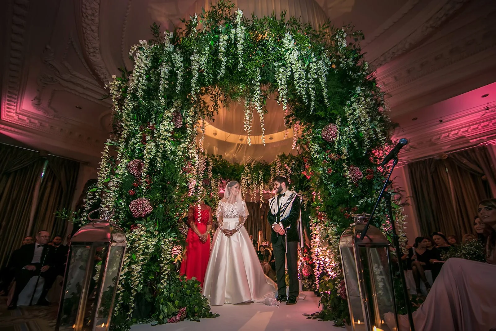 Manchester wedding photographer bride and groom under spectacular floral green chuppah during Jewish ceremony