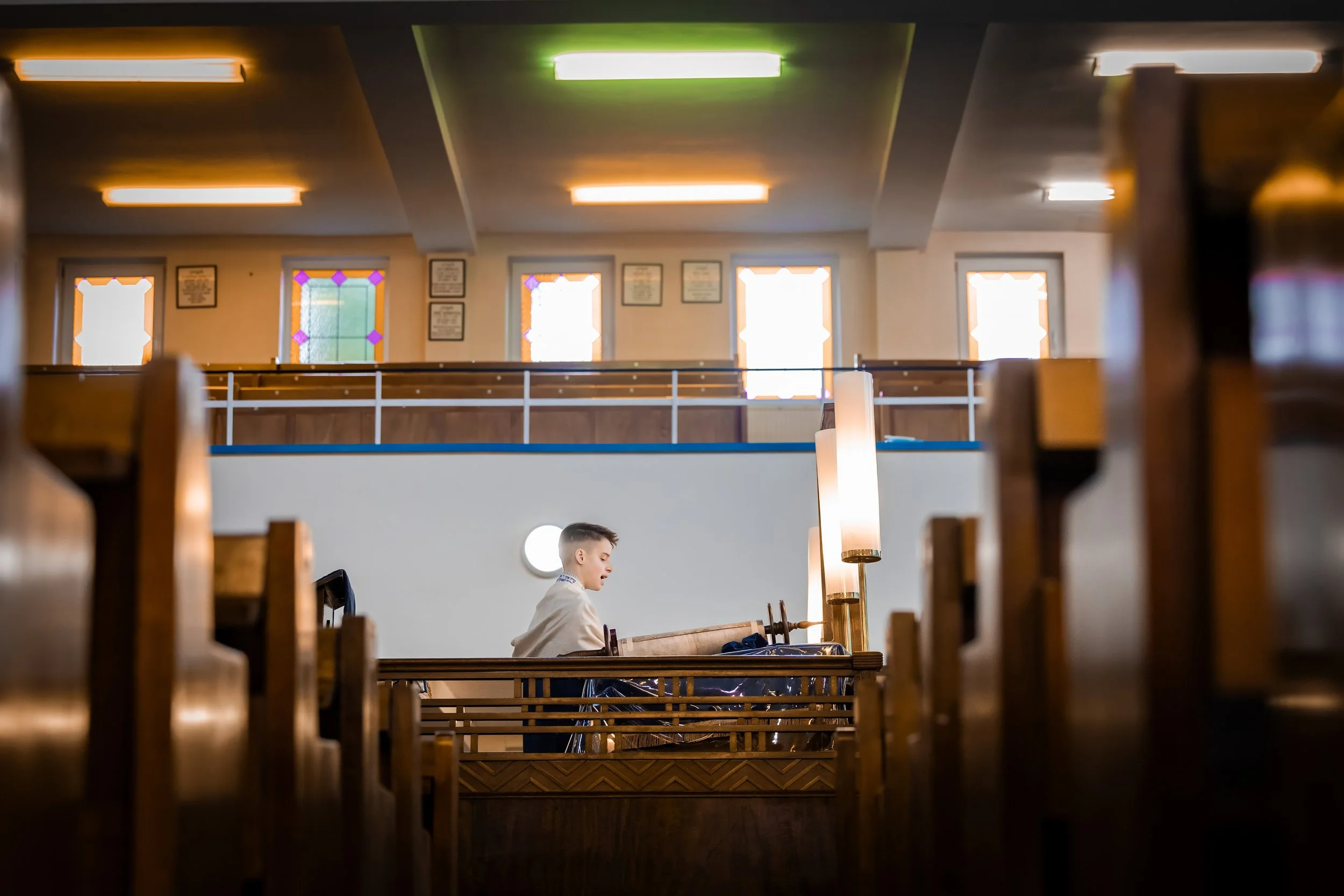 barmitzvah boy on bimah reciting from torah in synagogue in Manchester