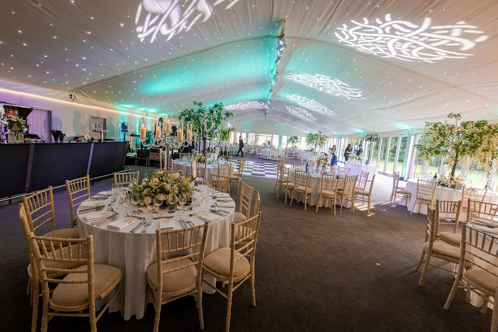 Nunsmere Hall marquee interior with teal ceiling lighting and projected pattern, daytime setup

