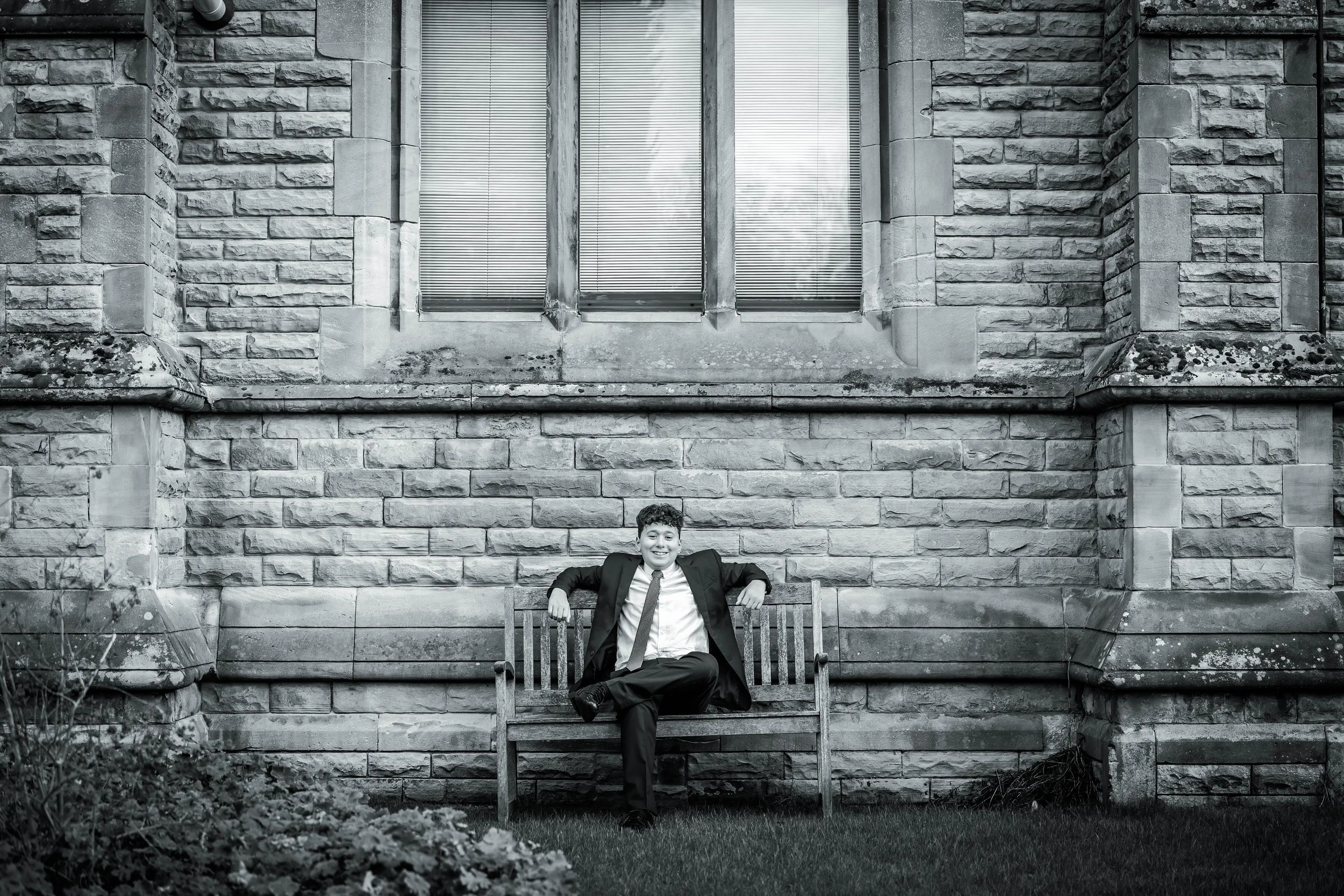 relaxed barmitzvah boy on bench in black and white outdoors