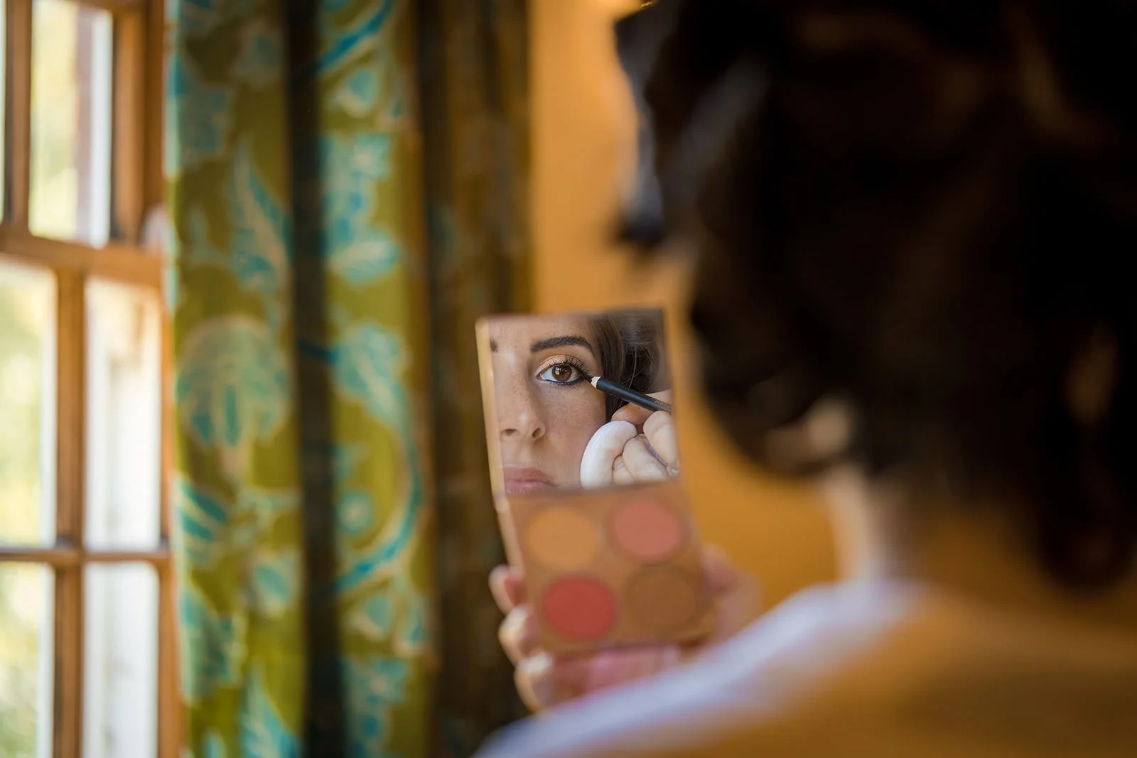 Bride checking makeup in mirror during morning preparations, Nunsmere Hall