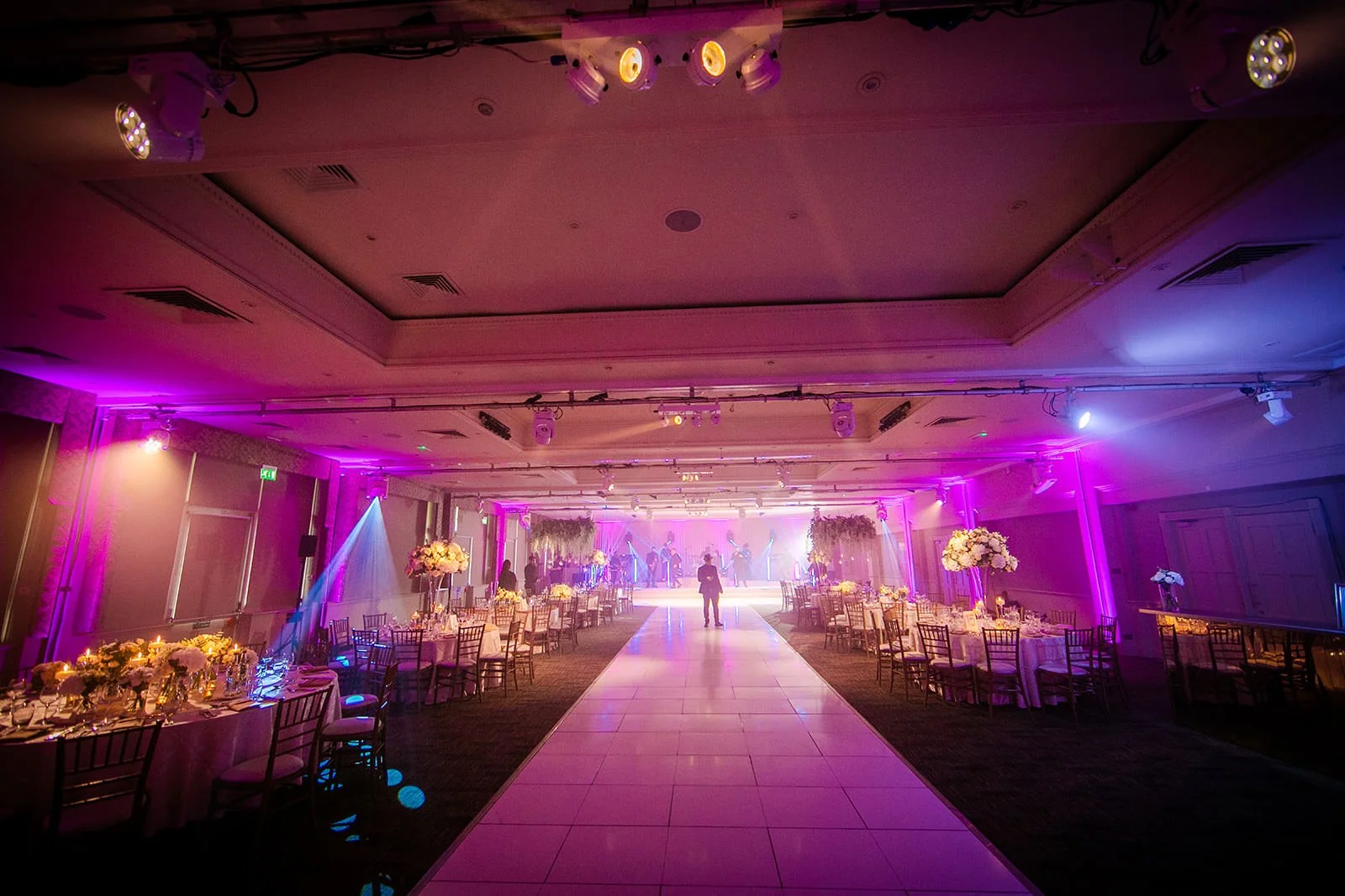 Pink-lit reception room with long white aisle, The Mere Knutsford wedding
