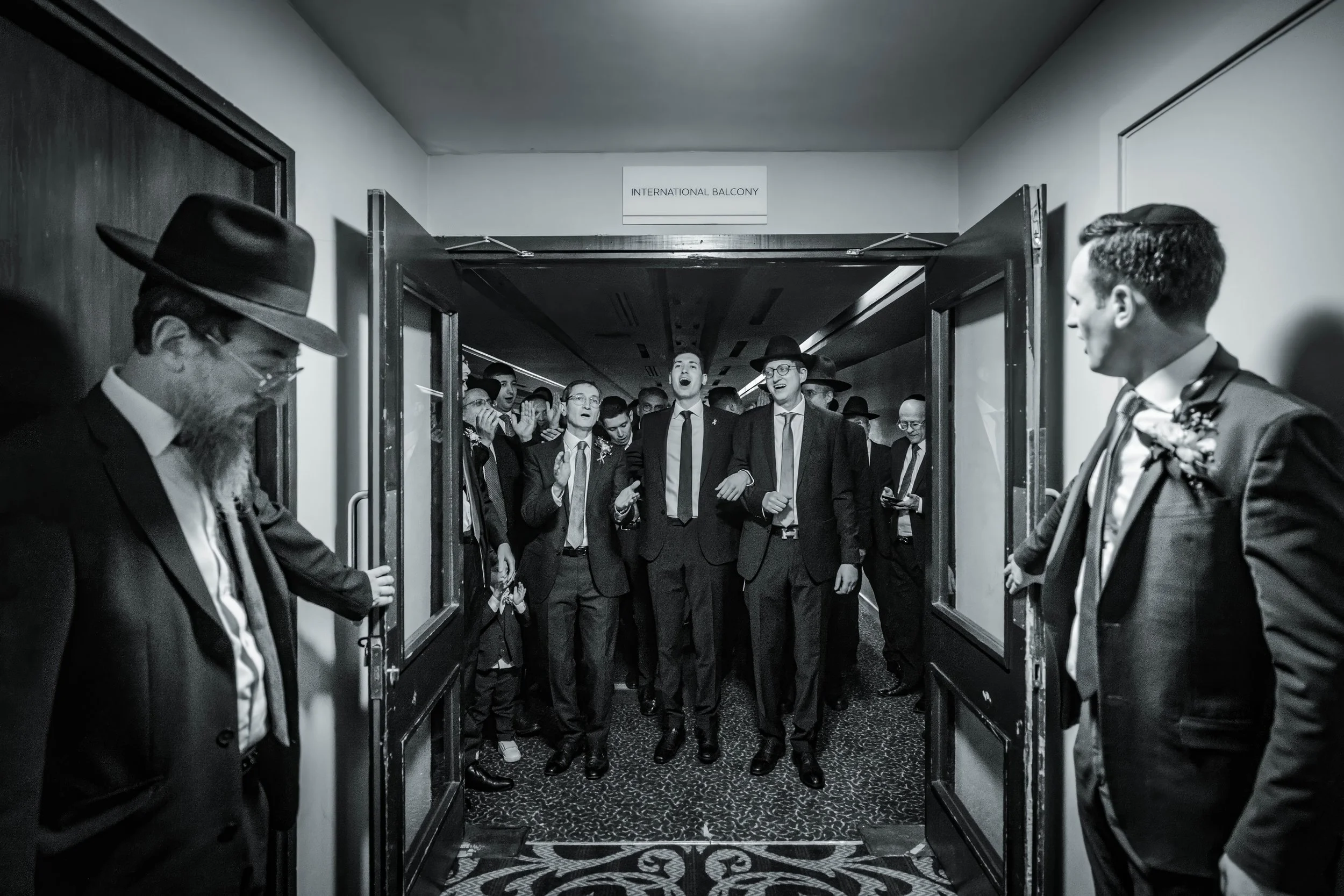 manchester jewish wedding photography captures groom walking to bedeken with dad and father-in-law