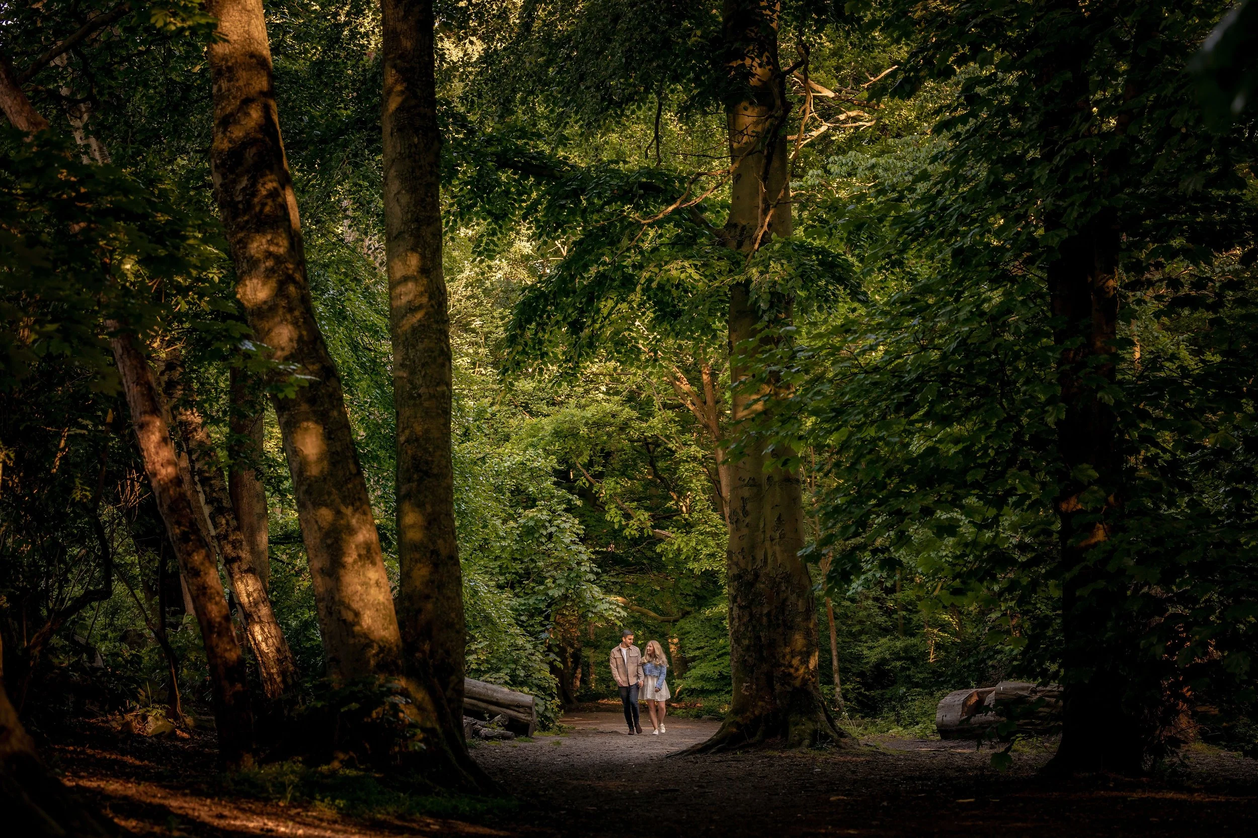 engagement shoot with couple walking amongst tall trees and woodland