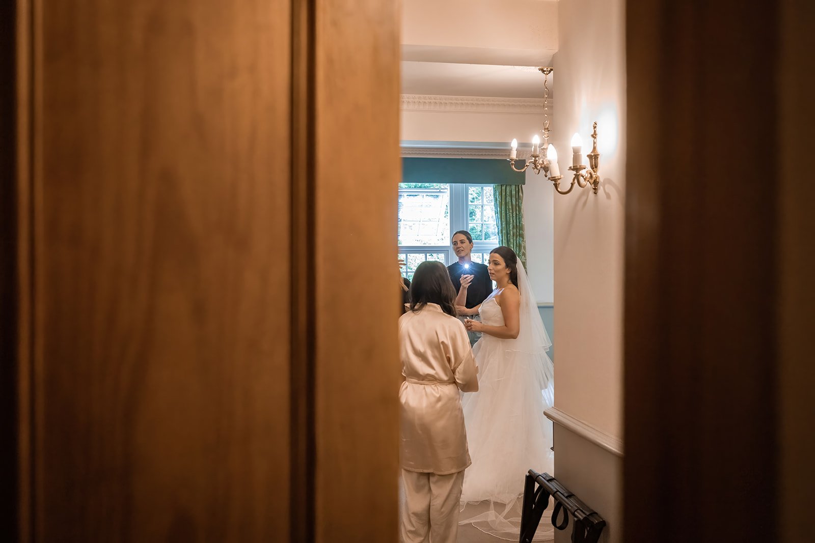 Bride having wedding dress fastened, intimate moment during bridal prep at Nunsmere Hall
