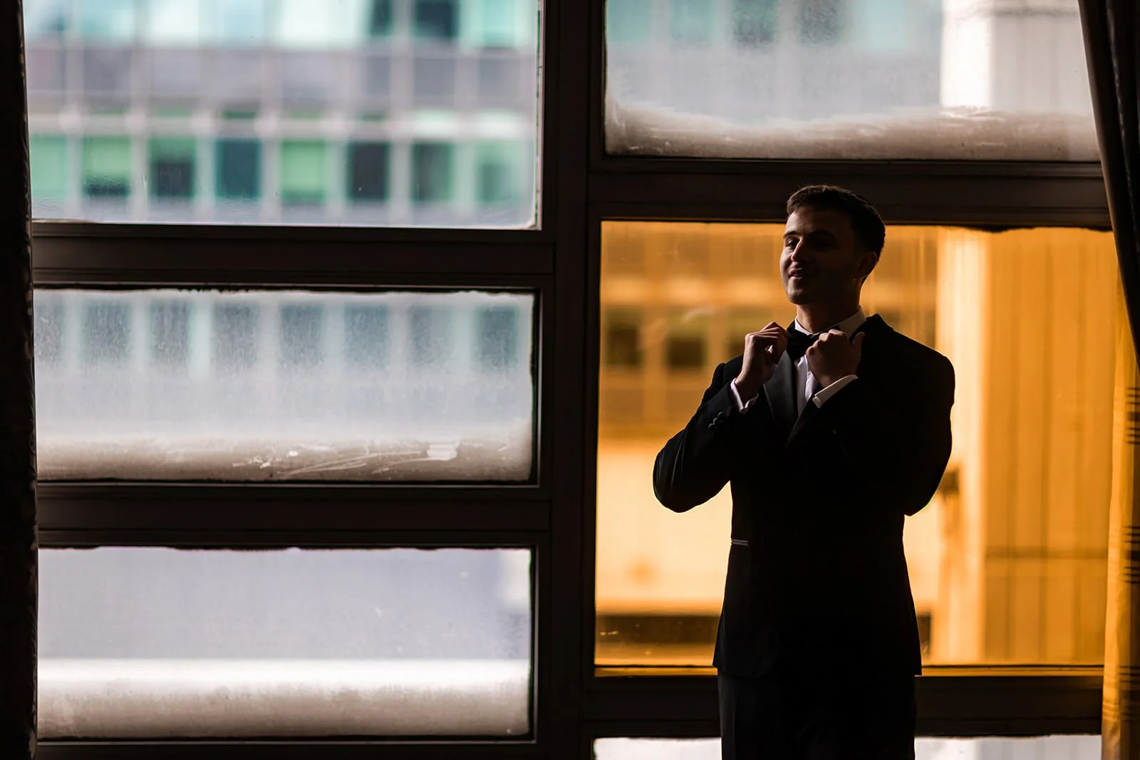 groom adjusts bow-tie during prep at mercure manchester piccadilly