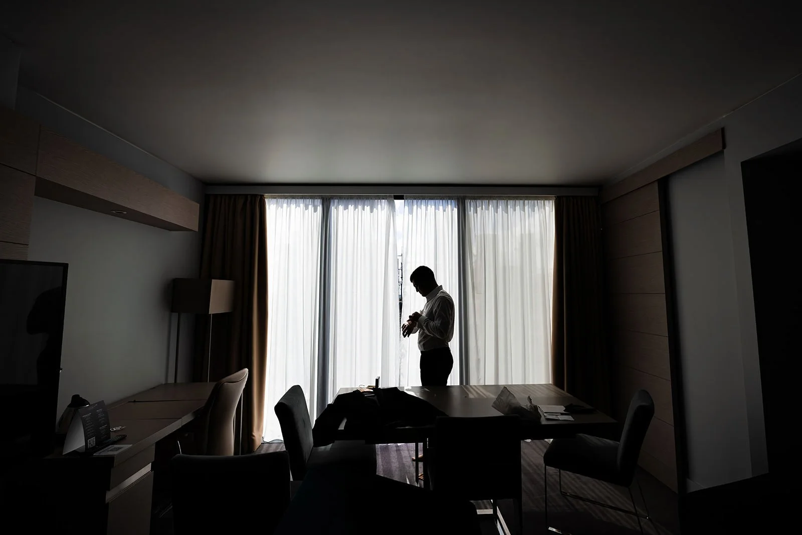silhouette of groom getting ready during prep at manchester deansgate hotel wedding venue