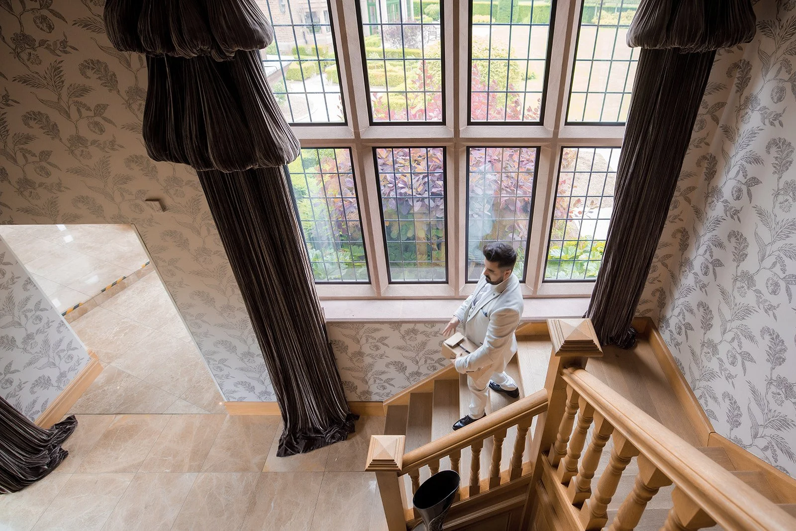 Merrydale Manor wedding groom in white suit on staircase – wedding photographer North West England